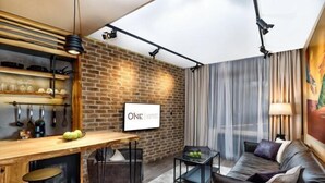 A modern living room with a brick wall, a wooden bar, and a sofa. - One Luxury Suites (Belgrade)