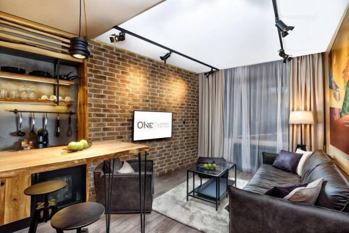 A modern living room with a brick wall, a wooden bar, and a sofa.