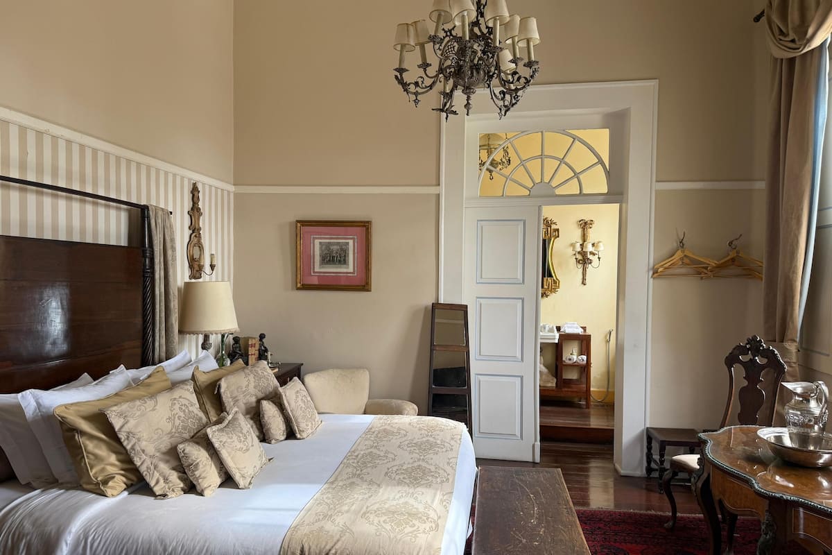 Une chambre à coucher avec un grand lit, un lustre, une commode et un miroir.