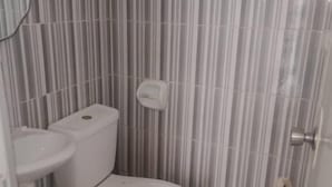 Een kleine badkamer met toilet, wastafel en een prullenbak.