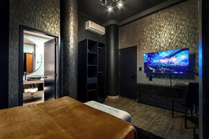 A modern room with a bed, a TV, and a bathroom.