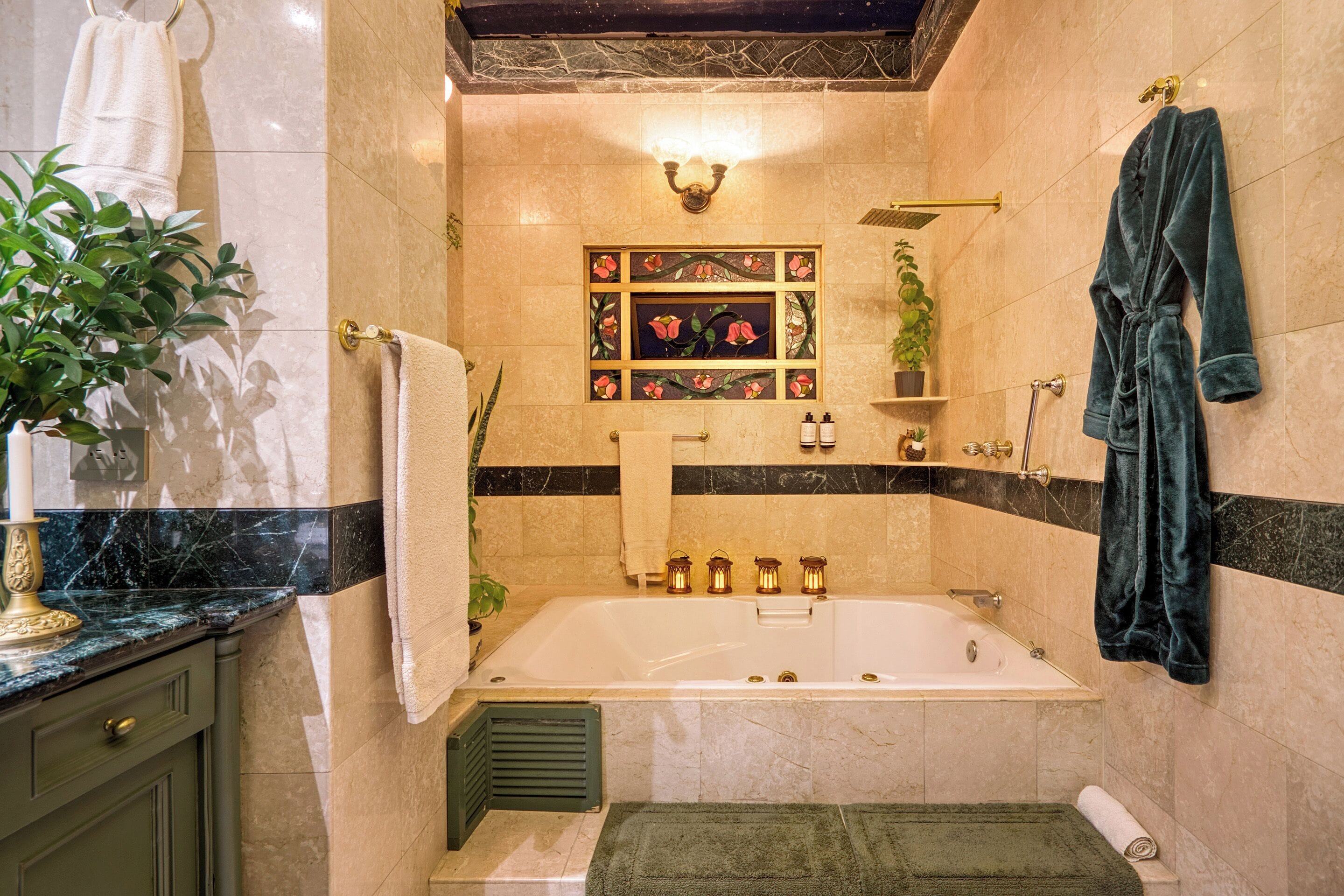 Un baño con bañera, tocador con espejo, perchero, planta en maceta y un panel decorativo en la pared.