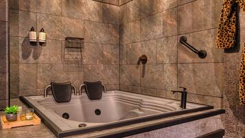 A modern bathroom with a large bathtub, a shower, and a towel rack.