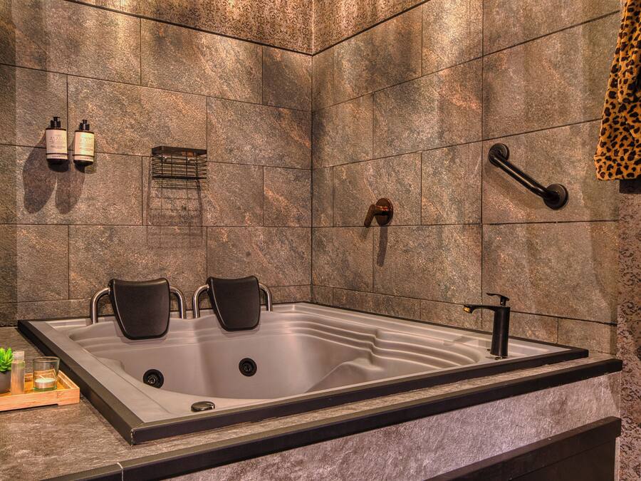 A modern bathroom with a large bathtub, a shower, and a towel rack.