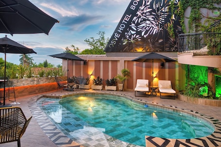 Una piscina al aire libre, sombrillas, sillones reclinables de piscina