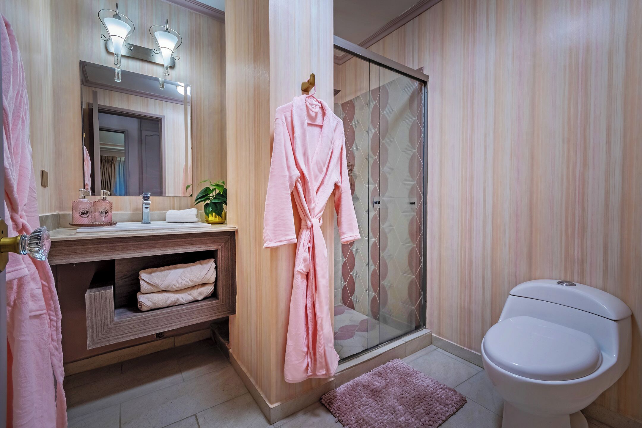 A bathroom with a wooden vanity, a glass shower enclosure, and a white toilet.
