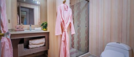 A bathroom with a wooden vanity, a glass shower enclosure, and a white toilet.