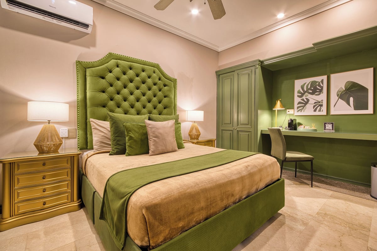 A neatly arranged bedroom with a tufted green headboard, a green bedspread, and matching green nightstands.