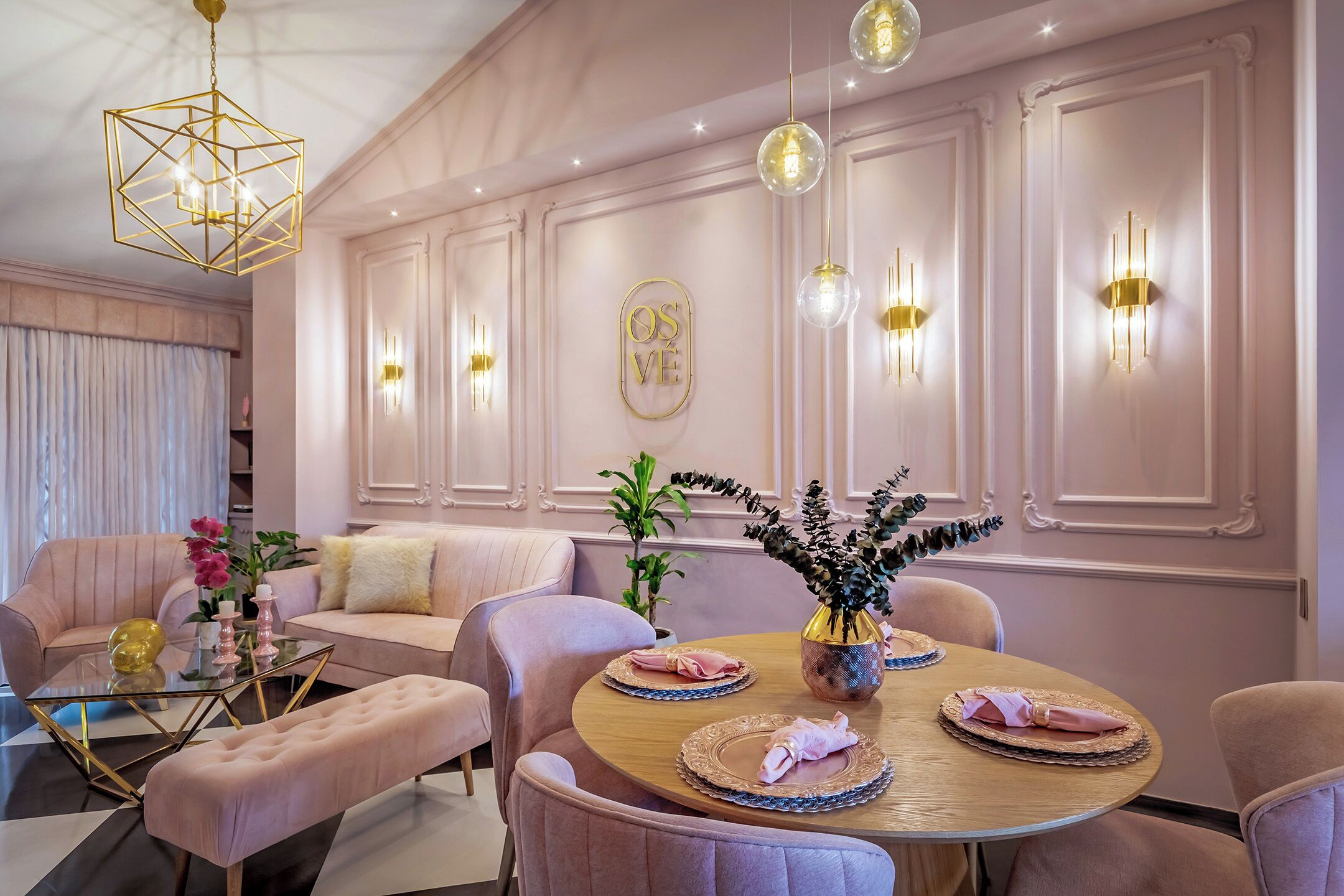 A dining area with a round table, pink upholstered chairs, and a central vase with flowers.