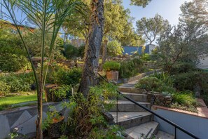 Un jardin agrémenté d’un escalier en pierre, de différentes plantes et d’un arbre.