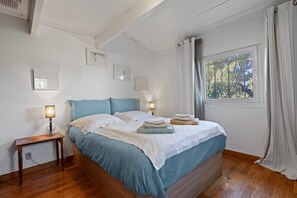 Une chambre à coucher avec un lit, des lampes de chevet, une fenêtre avec des rideaux et des tableaux encadrés accrochés au mur.