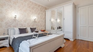 A bedroom with a large bed, white wardrobe, and a nightstand with a lamp. - Comfortable apartments in Minsk's Mayak (Minsk)