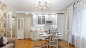 A modern kitchen with white cabinetry, a dining table with chairs, and a chandelier. - Comfortable apartments in Minsk's Mayak (Minsk)