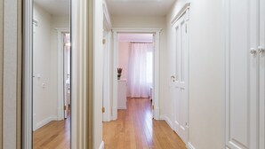 A hallway with wooden flooring, white walls, and doors on both sides. - Comfortable apartments in Minsk's Mayak (Minsk)