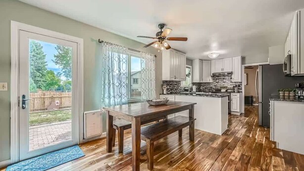 Une cuisine spacieuse avec un plancher en bois, une table à manger et un ventilateur de plafond.