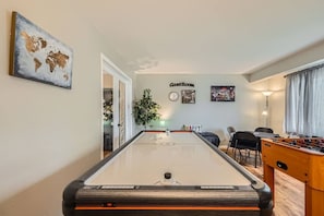 A pool table in a room with a world map, a clock, and a foosball table. - Pet + Family Friendly | Office | 30 Day | Longmont (Longmont)