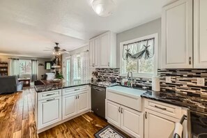 A kitchen with white cabinets, a black countertop, and a wooden floor. - Pet + Family Friendly | Office | 30 Day | Longmont (Longmont)