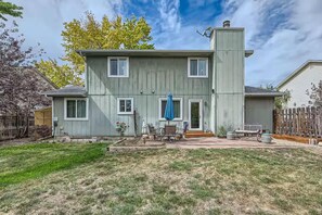 A two-story house with a covered patio, a chimney, and a fenced yard. - Pet + Family Friendly | Office | 30 Day | Longmont (Longmont)