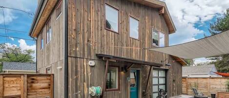 Una casa a due piani in legno con garage, portico coperto e posti a sedere esterni.