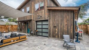 Uma casa de madeira com garagem, área de estar externa e uma bicicleta.