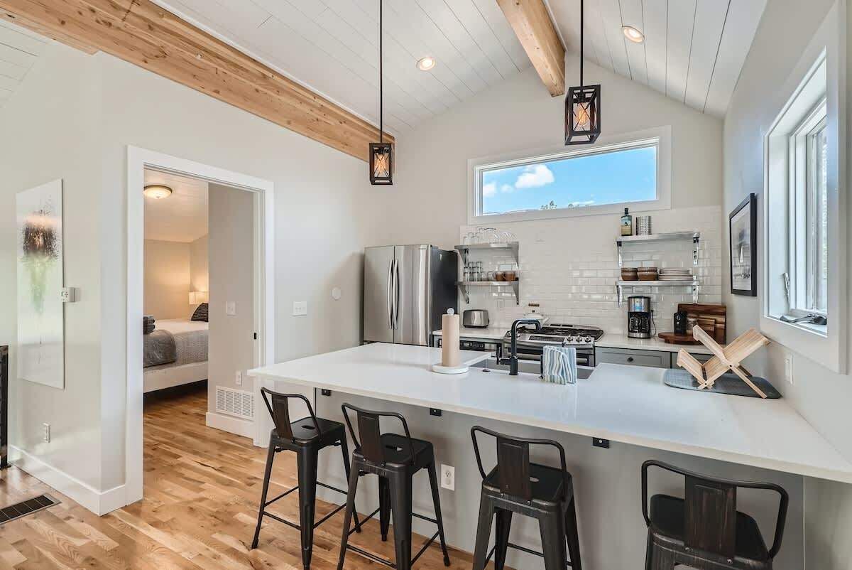Una cocina moderna con una isla grande, taburetes de bar y vistas al dormitorio contiguo.
