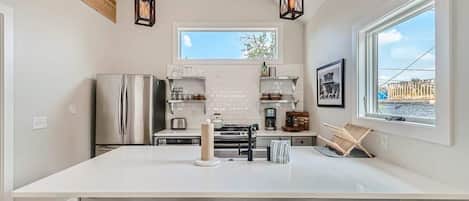 A modern kitchen with a large island, stainless steel appliances, and a view of the outdoors.