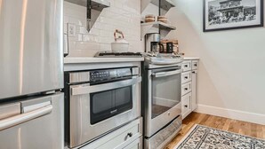 Uma cozinha com eletrodomésticos de aço inoxidável, painel de azulejos branco e uma fotografia emoldurada na parede.