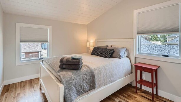 Um quarto com uma cama, uma mesa de cabeceira, uma janela com persianas e uma luminária no teto.