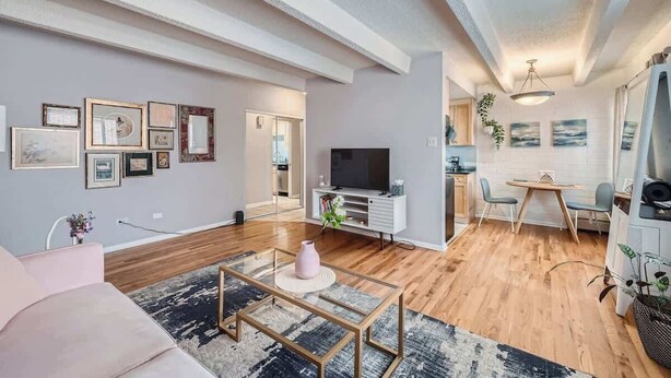 Una sala de estar moderna con un sofá, una mesa de centro y un televisor. Hay un comedor con una mesa y sillas.