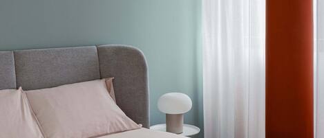 A modern bedroom with a bed, a bedside table, and a lamp.