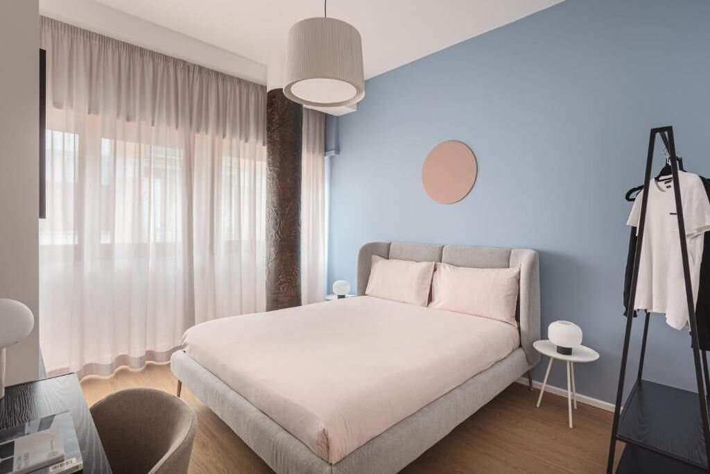 A modern bedroom with a large bed, a round mirror, and a clothing rack.