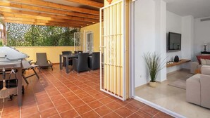 Eine überdachte Terrasse mit Billardtisch, Stühlen und Essbereich.