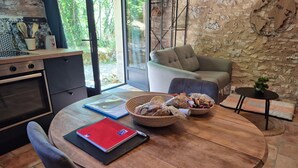 A dining area with a round wooden table, a red notebook, a blue folder, and a basket of snacks. - Gite Le Soupadou – La Framie – Charm, Comfort and Nature in Albas (Albas)