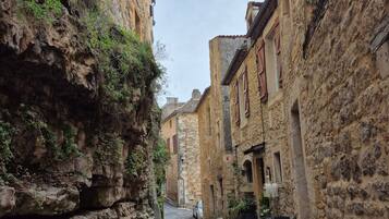 Une ruelle étroite, bordée de bâtiments en pierre, avec un chemin pavé et une voiture garée.