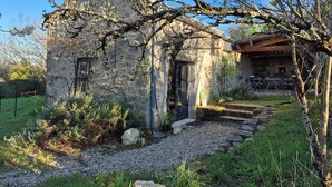 Un edificio rustico in pietra con tetto in tegole, una porta in legno e un piccolo portico.
