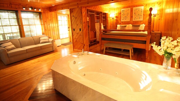 A wooden interior with a large bathtub, a sofa, and a bench.