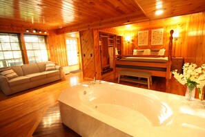 A wooden interior with a large bathtub, a sofa, and a bench. - Haus in the Heart of Helen - Lower Level Suite (Helen)