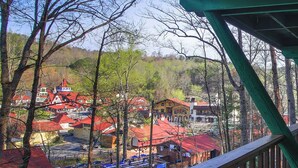 A town with red-roofed buildings, a wooden bridge, and a forested hillside.