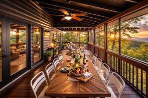 Un espace extérieur abrité, aménagé pour les repas, avec une table en bois prévue pour quatre personnes, entourée de chaises blanches, et offrant une vue sur un paysage boisé.