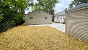 A residential area with two houses, one with a visible chimney and a yard covered with straw mulch. - Amazing 2-bedroom house with AC in Eastlake (Eastlake)