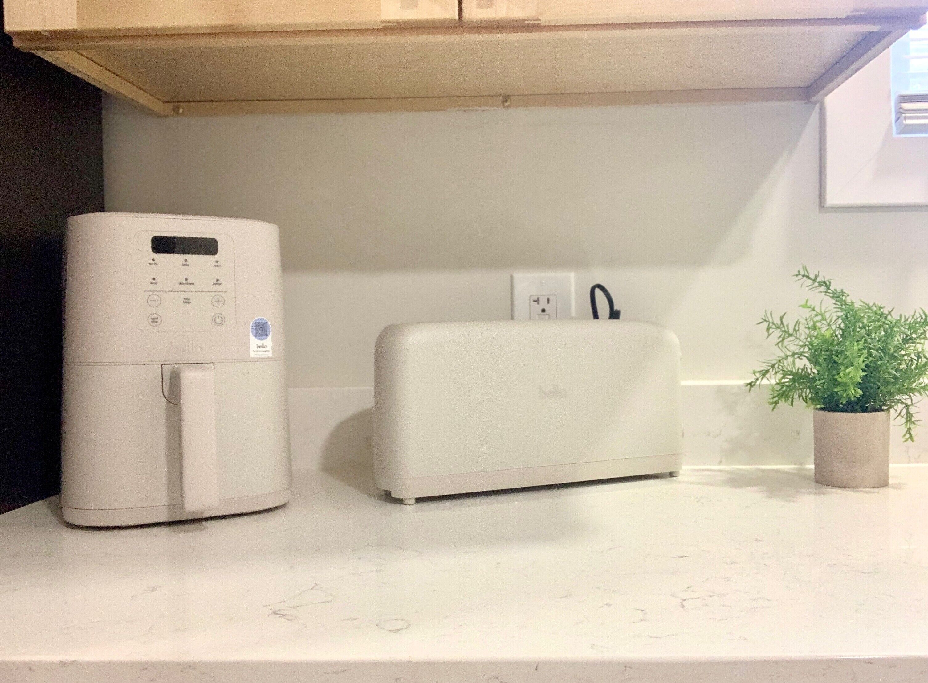 Una cocina con encimera blanca, electrodoméstico blanco y una planta en maceta.