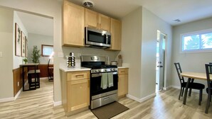 A compact kitchen with wooden cabinets, a microwave, a stove, and a sink. - Amazing 2-bedroom house with AC in Eastlake (Eastlake)