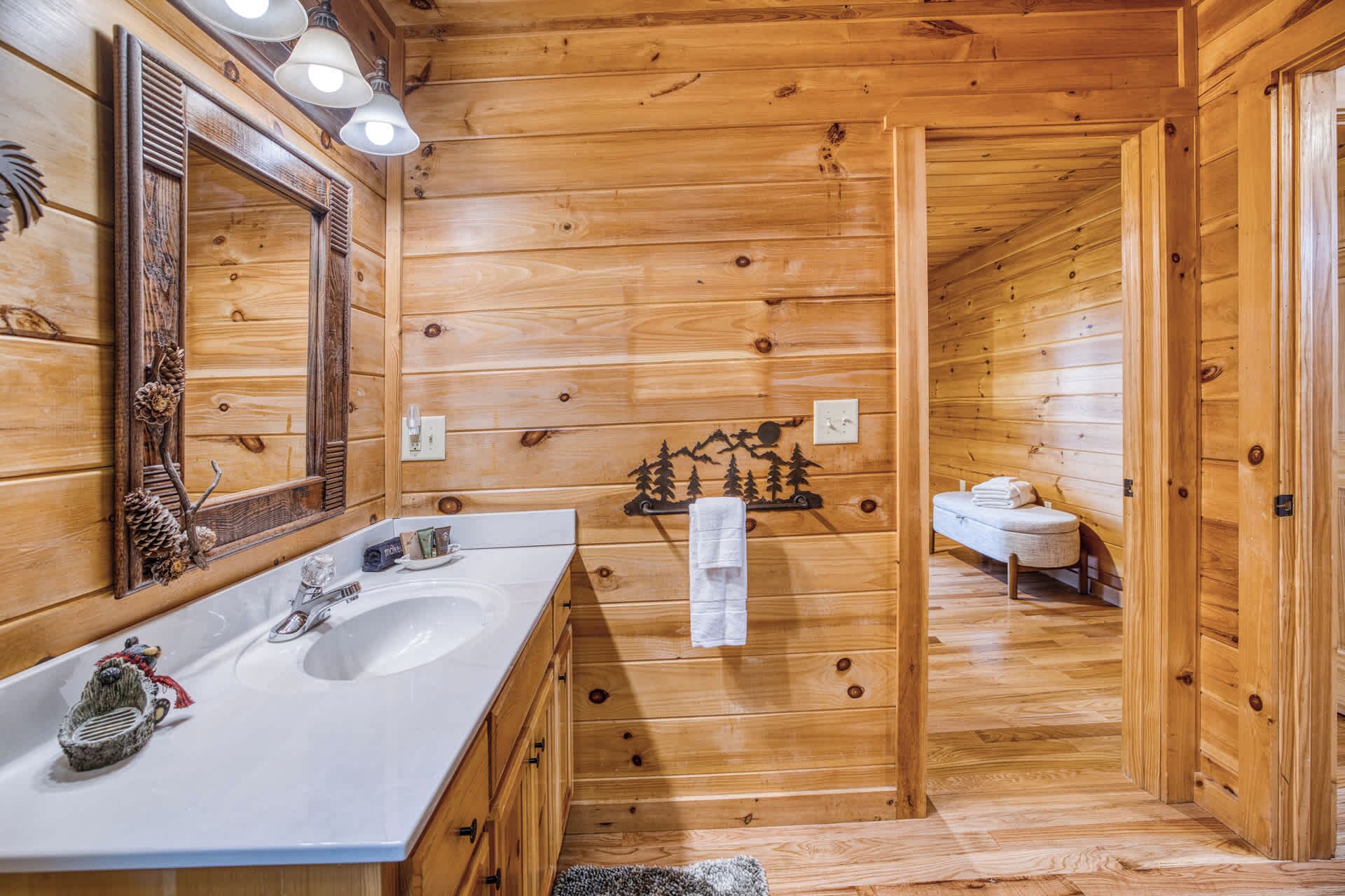 Ein Badezimmer einer Holzhütte mit Waschbecken, Spiegel und Handtuchhalter.