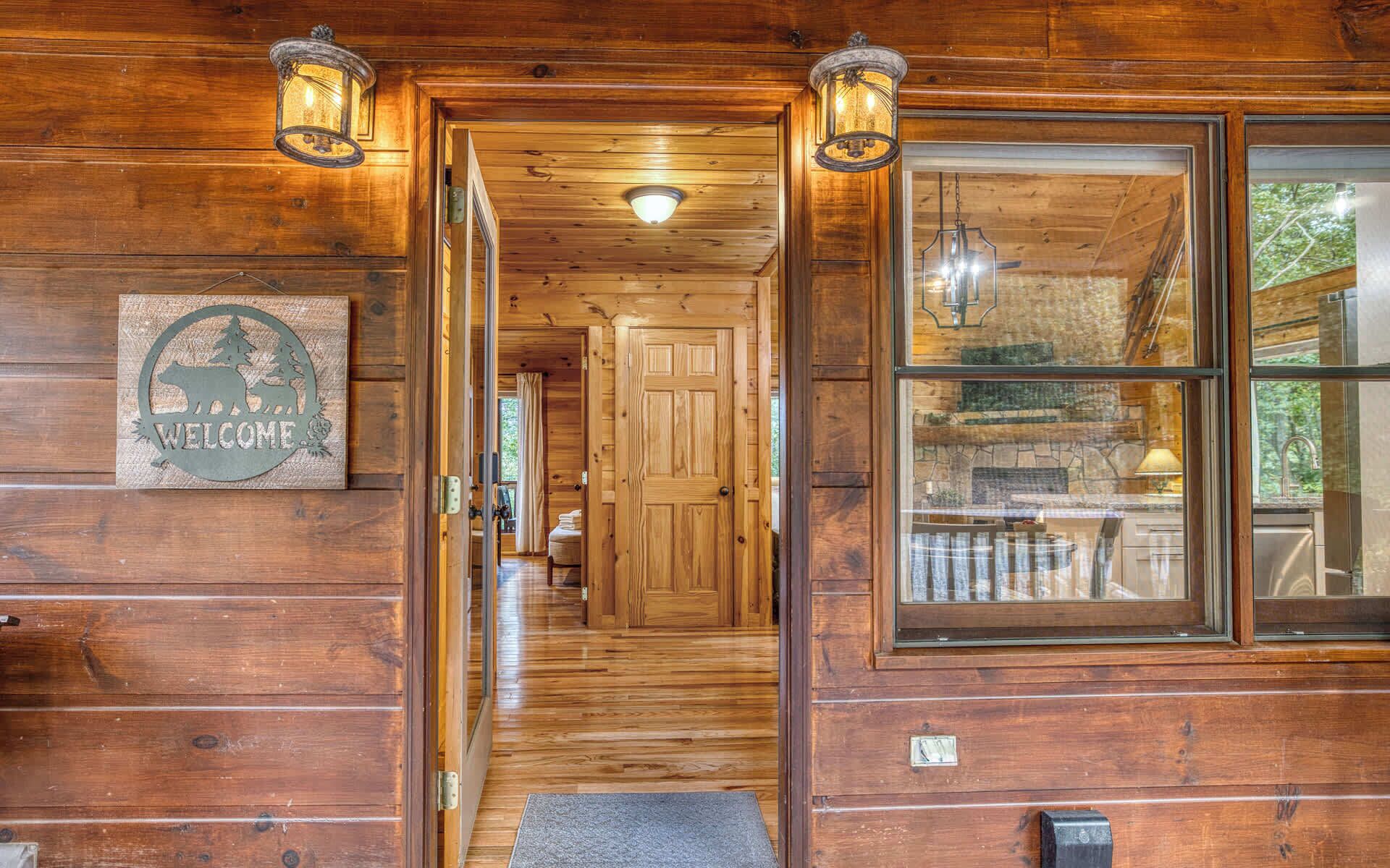 L’intérieur d’un chalet en bois, avec une porte en bois, une pancarte de bienvenue, un escalier et une fenêtre.