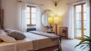 Un dormitorio con una cama de madera, un espejo redondo, una mesita de noche con una lámpara y una silla.
