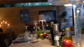 Una mesa de madera con platos, vasos y diferentes condimentos.