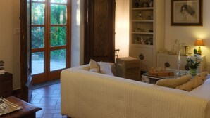 Un dormitorio acogedor con una cama grande, vigas de madera, una estantería y una puerta que da a un jardín.