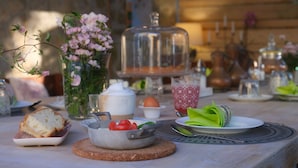 Una mesa dispuesta con comida y bebidas, un florero y una cesta de pan.