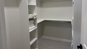 Un dressing ouvert avec des étagères blanches et une tringle à vêtements, où les serviettes sont soigneusement pliées.