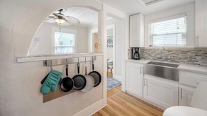 A modern kitchen with white cabinets, a stainless steel sink, and a ceiling fan.